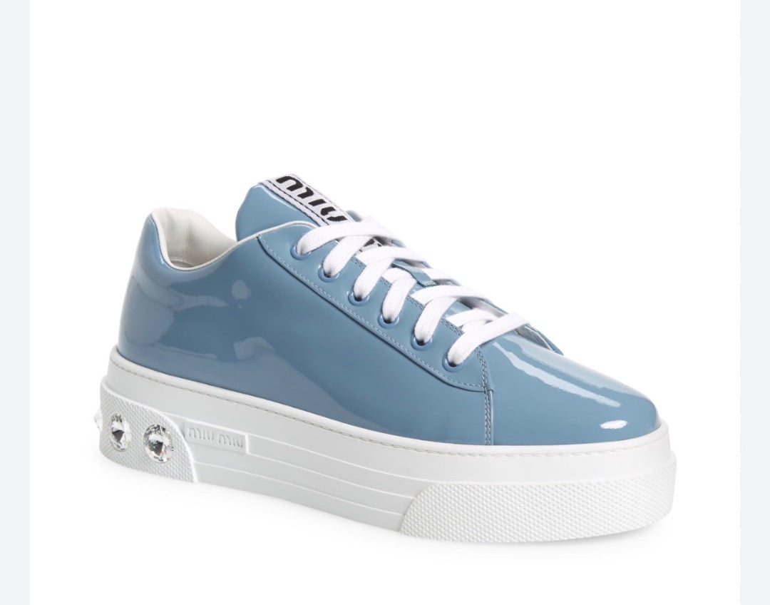 Miu Miu platform sneakers featuring a patent leather upper and logo-embellished tongues.