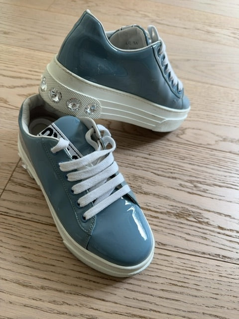 Miu Miu platform sneakers featuring a patent leather upper and logo-embellished tongues.